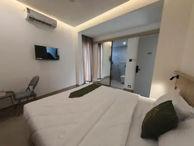 a bedroom with a large white bed and a television at The Zen Retreat in Kozhikode