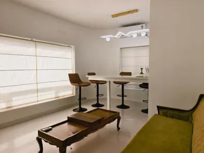 a living room with a table and chairs and a window at Ambadis private pool villa in Pallipuram
