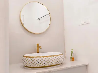 a bathroom with a round mirror above a sink at Ambadis private pool villa in Pallipuram