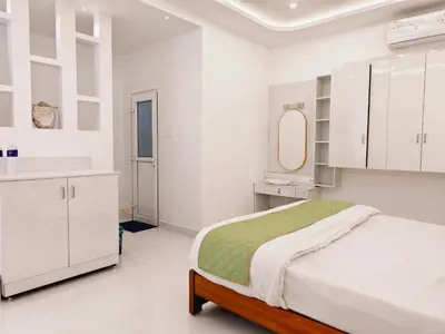a white bedroom with a bed and a mirror at Ambadis private pool villa in Pallipuram