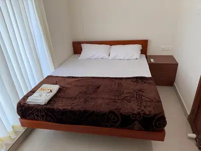 a small bedroom with a bed with a brown blanket at Balcony inn in Nedumbassery