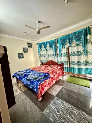 a bedroom with a bed and a window with blue curtains at Mysore City Center Rooms by A1k in Mysore