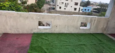 a concrete wall with two windows and green grass at SARA'S LUXURY stay in Coimbatore (Peelamedu)