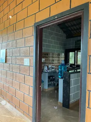 a brick wall with a doorway into a kitchen at Cozy Tiny Farm Stay in Mysore