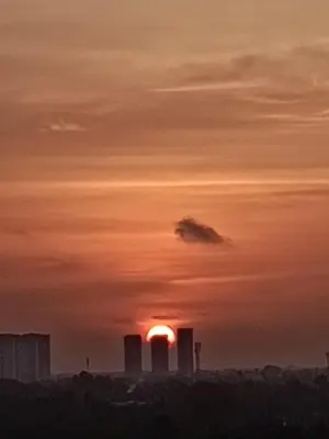a sunset with the sun setting behind some buildings at Property near cochin international airport in Alwaye