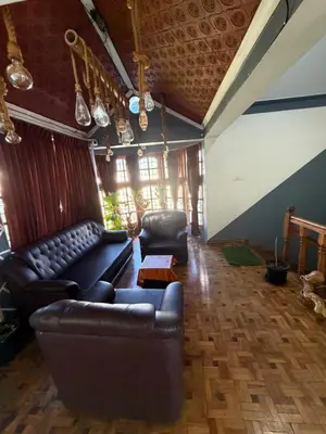 a living room with a leather couch and a table at DM&sons guesthouse in Coonoor