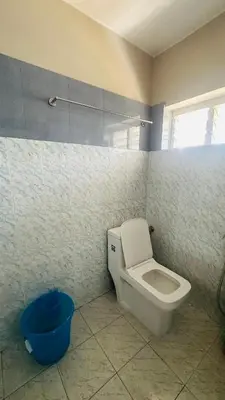 a bathroom with a toilet and a blue bucket at Grace villa in Kunnamkulam