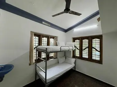 a room with two bunk beds and a ceiling fan at Sreekrishnapuram Family Retreat in Karimpuzha