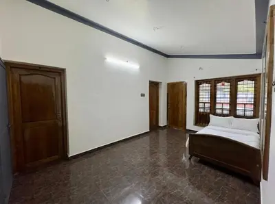a bedroom with a bed and two windows in it at Sreekrishnapuram Family Retreat in Karimpuzha
