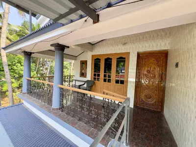 a porch of a house with a wooden door at Sreekrishnapuram Family Retreat in Karimpuzha