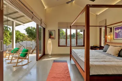 a bedroom with a canopy bed and a patio at SaffronStays Chandra Amara in Bengaluru
