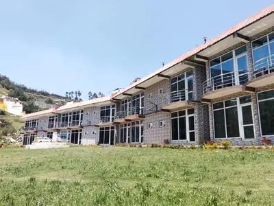 a large brick building with a field in front of it at TULIPS VILLAGE RESORTS - A Valley View Abode in Ooty