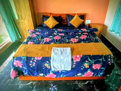 a bed with a blue comforter with a towel on it at Sun Side Cottages in Madikeri
