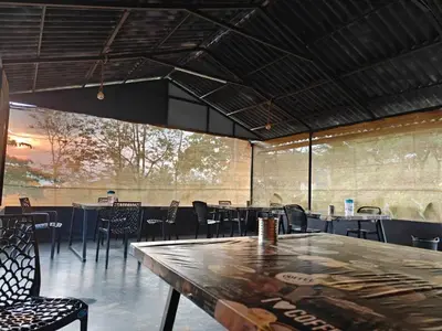 a dining room with tables and chairs and a large window at spiritofthewild in Attappādi