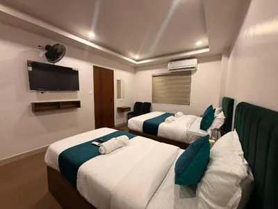 a hotel room with two beds and a flat screen tv at Ellora grand hotel in Kozhikode