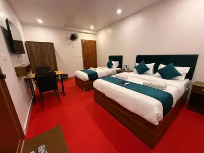 a hotel room with two beds and a desk with a computer at Ellora grand hotel in Kozhikode