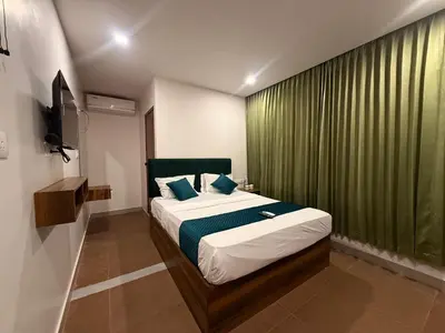a bedroom with a bed with a green curtain at Ellora grand hotel in Kozhikode