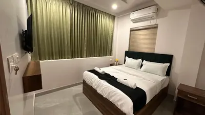 a bedroom with a bed with a green curtain and a window at Ellora grand hotel in Kozhikode