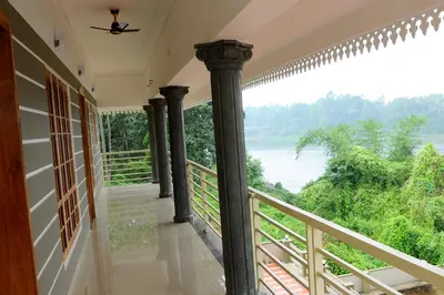 a room with a balcony with a view of a river at SHANKARAM Homestay in Kodanad