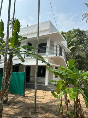 a white house with palm trees in front of it at VYSHNAVI 2BHK AC Apartment in Thanniyam