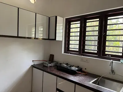 a kitchen with a counter and a sink and windows at Nilavu Homes Retreat in Wayanad