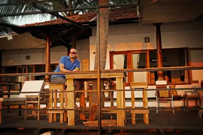 a man sitting at a table in a room with chairs at 36 Palms Boutique Retreat in Cherai Beach