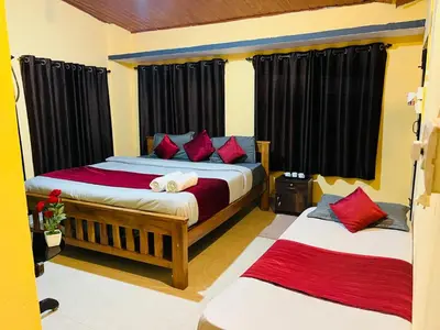 two beds in a room with black curtains and red pillows at Coorgkushihomestay in Madikeri