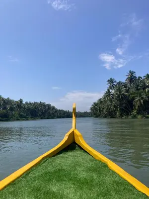 a yellow boat on the water with trees in the background at Kakkakuni heritage in Kozhikode