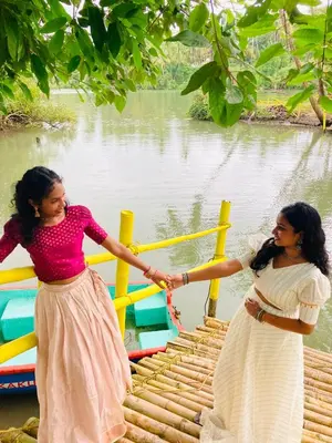 two women holding hands while standing near a body of water at Kakkakuni heritage in Kozhikode