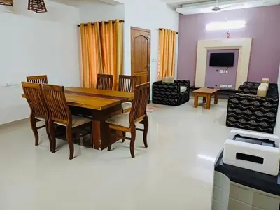 a dining room with a wooden table and chairs at very spacious furnished apartment in Guruvāyūr