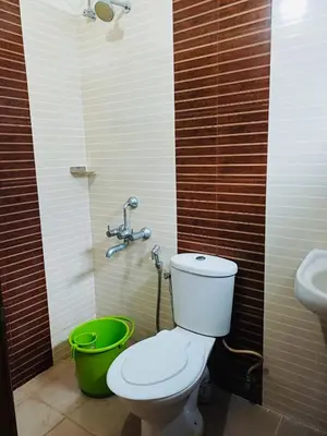 a bathroom with a toilet and a green bucket at very spacious furnished apartment in Guruvāyūr