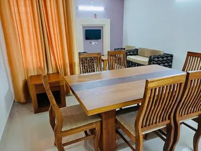 a dining room with a wooden table and chairs at very spacious furnished apartment in Guruvāyūr