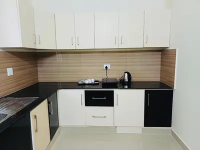 a kitchen with white cabinets and black counter tops at very spacious furnished apartment in Guruvāyūr