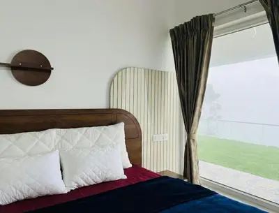 a bedroom with a bed and a window at Bison Trails Valley View Kothagiri Ooty Tamilnadu in Kotagiri