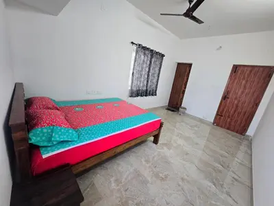 a bedroom with a bed with a red and green comforter at Eachanari Karpaga Rathinam Residency By Shivalaya Stays in Coimbatore