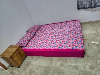 a bed in a room with a pink mattress and a table at Eachanari Karpaga Rathinam Residency By Shivalaya Stays in Coimbatore