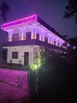 a white building with a neon sign on it at night at Poozhikuth Homestay in Sultan Bathery