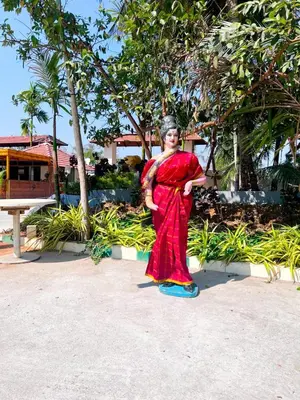 a woman in a red dress standing on the beach at Bombe Resort Channapatna in Channapatna