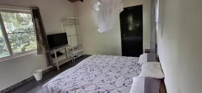 a bedroom with a bed and a tv and a window at Echupary Estate cottage in Gonikoppal