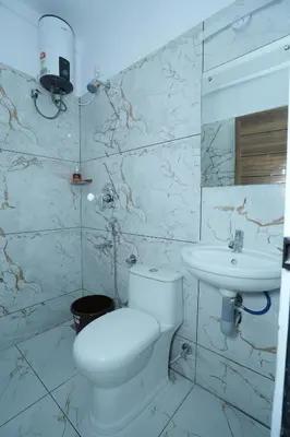 a white bathroom with a toilet and a sink at Janaki Heavens, 1 BHK Apartment in Guruvāyūr