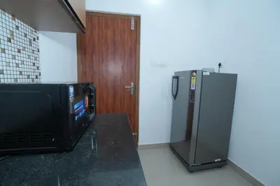 a microwave sitting on a counter next to a refrigerator at Janaki Heavens, 1 BHK Apartment in Guruvāyūr