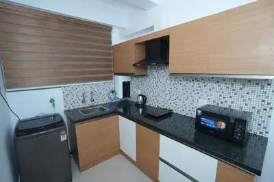 a small kitchen with a sink and a refrigerator at Janaki Heavens, 1 BHK Apartment in Guruvāyūr