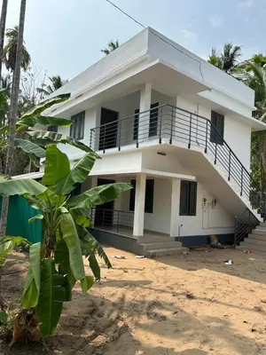 a white house with a palm tree in front of it at Vyshnavi 2 BHK AC Apartment in Thanniyam