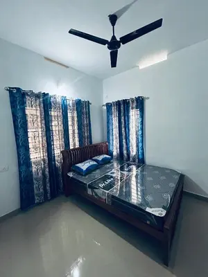 a bed in a room with a ceiling fan at Vyshnavi 2 BHK AC Apartment in Thanniyam