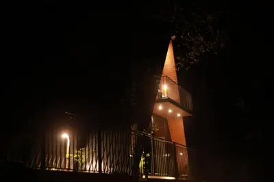 a church at night with a fence and lights at Hill wood nature touch resort in Pinangode