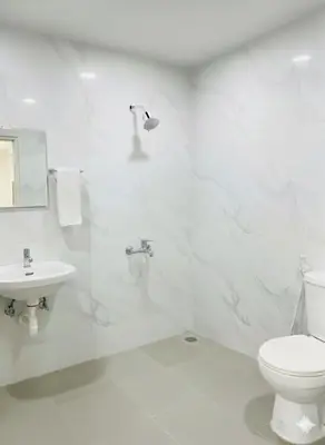 a white bathroom with a toilet and a sink at Forum Stay in Mysore