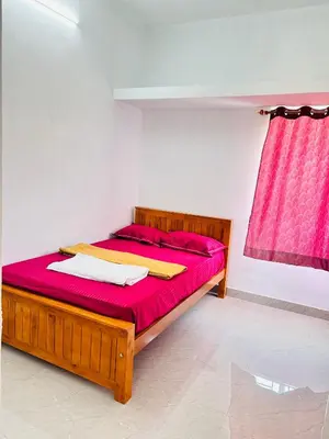 a bedroom with a bed with red sheets and a pink curtain at AAG Pride serviced apartments in Pollāchi