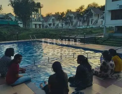 a group of people sitting around a swimming pool at The NEST VILLAS in Athirappilly