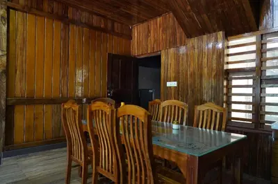a dining room with a wooden table and chairs at JackRoot Athirappilly in Kallana