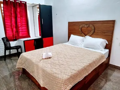 a bedroom with a bed with two white shoes on it at Flavoury Restaurant & Rooms in Paithalmala